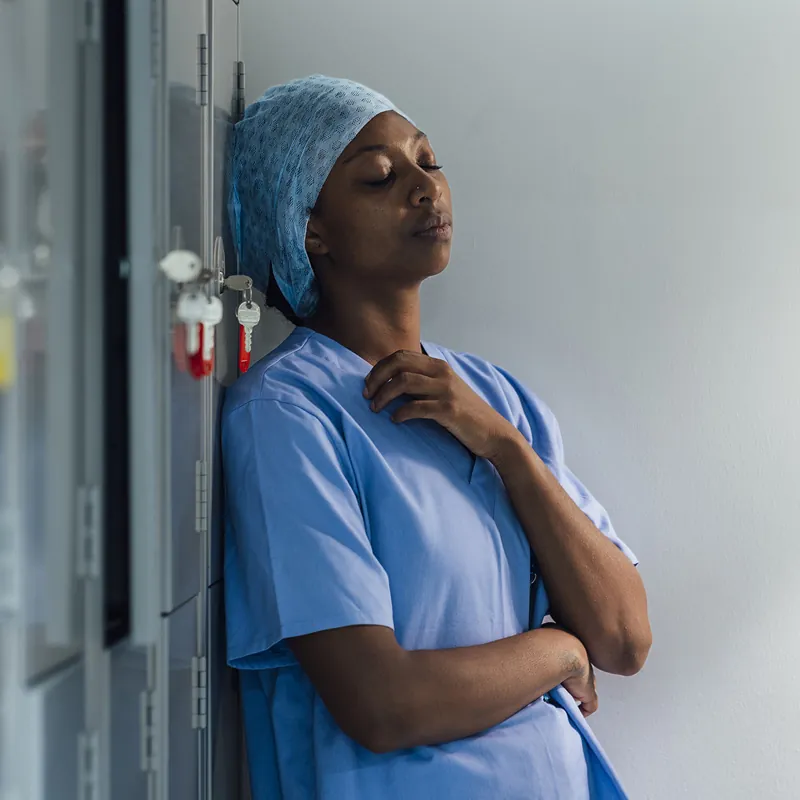 A surgical staff member leaning against a wall