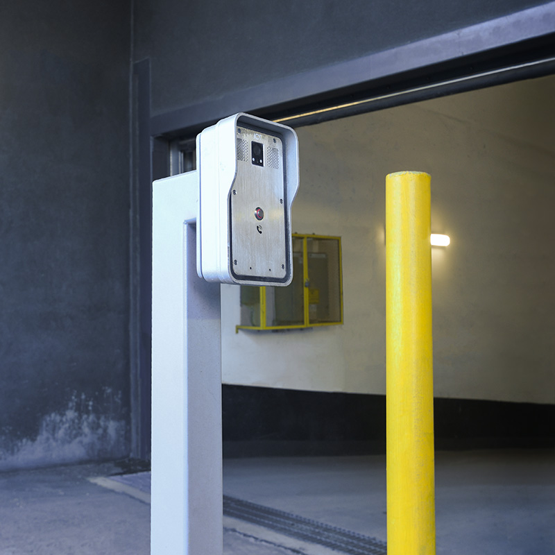 A grey intercom at the entrance to a parking garage