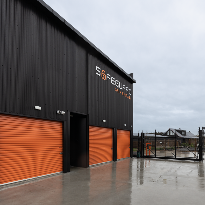 External of black self storage building with orange roller doors